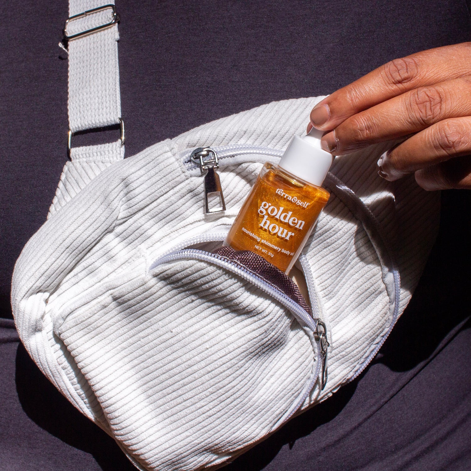 Woman pulling mini Golden Hour Body oil out of her fanny pack