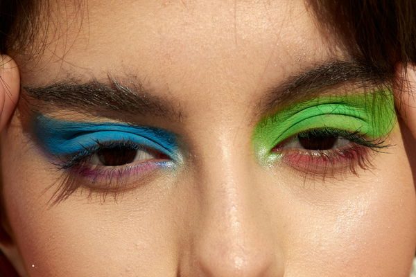 Person with bold blue and green eyeshadow, close-up on eyes, colorful makeup look
