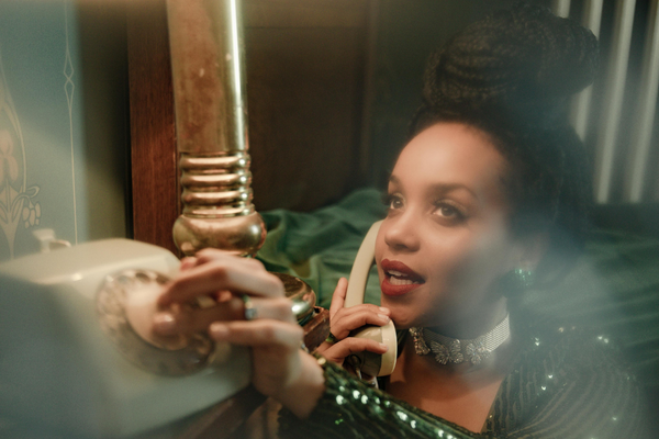 Woman in glamorous outfit talking on a vintage rotary phone, elegant retro setting